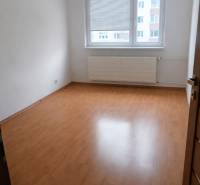 A room with a wooden decor floor in a 3-room apartment, with a bright interior and a window.