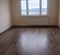 A room with a large window, a floor with a wooden decor in a 3-room apartment.