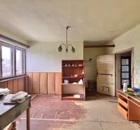 A room in a family house with furniture, shelves, and a large window.