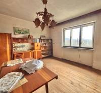A room in a family house with wooden decor, vintage furniture, a chandelier, and a large window.