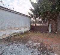 Land in Radzovce with an unplastered wall, metal gate, and conifer. Land - residential.