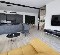 Living room with kitchen in a family house, wooden decor flooring and a yellow sofa.