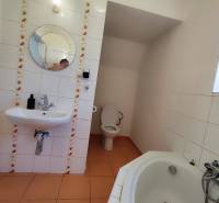 A bathroom in a family house with a round mirror, toilet, and bathtub.