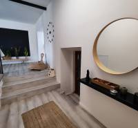 Interior of a family house with a wooden decor floor, a round mirror, and houseplants.
