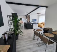Dining room and living room with a sofa, table, and floor with a wooden decor in a family house.