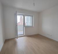 A room in a 2-room apartment with a wooden decor floor and a balcony.