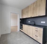 A kitchen in a 2-room apartment with a wooden decor floor and ceramic tiles.