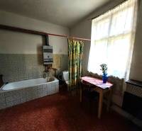 A bathroom in a family house with an older bathtub and a small table by the window.