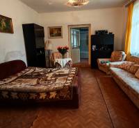 Living room in a family house with flowers, a sofa, and a wooden-patterned floor.