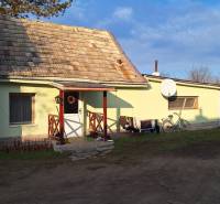 A family house in Rapovce with a veranda, a satellite dish, and a bicycle leaning against the wall.