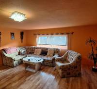A living room in a family house with orange walls and a wooden decor floor.