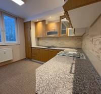 A kitchen in a 3-room apartment with a wooden decor floor and a modern kitchen unit.