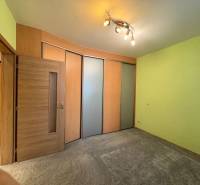 A room in a 3-room apartment with sliding doors, green walls, and spot lighting.