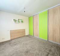 A room in a 3-room apartment with carpeted flooring and a built-in wardrobe with green sliding doors.