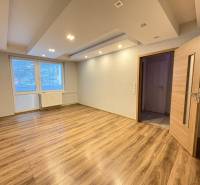 A room in a 3-room apartment with a wood-patterned floor and a large window.
