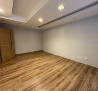 An empty room with wood-patterned flooring, white walls, and lighting in a 3-room apartment.