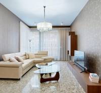 Living room in a 3-room apartment with a beige sofa, glass table, and television.
