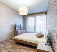 A bedroom in a 3-room apartment with a wood-patterned floor, floral wallpaper, television.