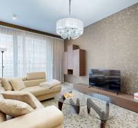 Living room in a 3-room apartment with a beige sofa, patterned wall, and glass table.