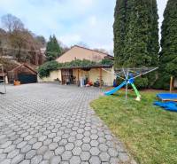 Courtyard at the Bank on Lesná Street with a playground, trees, and a paved surface.