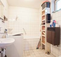 Bathroom in a family house with a bathtub, sink, washing machine, and shelving storage space.