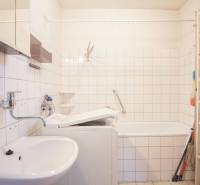 Bathroom in a family house with a bathtub, sink, and washing machine, white tiles.