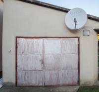 A garage with white doors next to a family house on Pod kopcom Street in Nové Zámky.