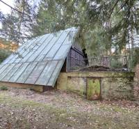 A cottage in the Krpáčovo forest on Krpáčovo street with a metal roof and a stone plinth.