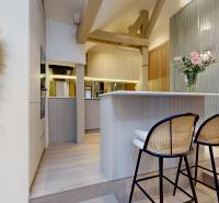 Interior of a 4-room apartment with bar stools, a decorative wall, and flowers in a vase.