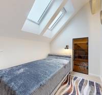 A bedroom in a 4-room apartment with large skylights and carpet.