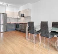 A kitchen in a 3-room apartment with a wooden decor floor, a glass-ceramic table, and chairs.