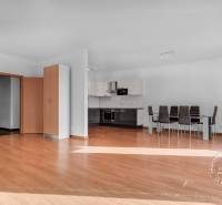 Living room with kitchen in a 3-room apartment, wooden decor flooring, dining area.