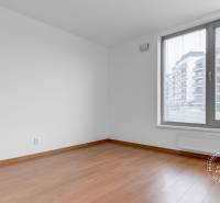 A room in a 3-room apartment with a window, wooden decor flooring, white walls.