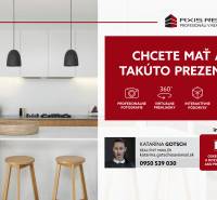 A kitchen with a light-colored countertop, an island, two wooden chairs, and pendant lights.