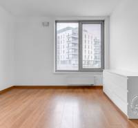 An empty room with a wooden decor floor and a white dresser in a 3-room apartment.