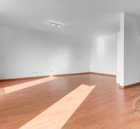 An empty living room in a three-room apartment with a wooden decor floor.