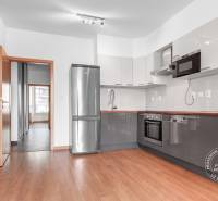 A kitchen in a three-room apartment with a wooden decor floor and a modern kitchen unit.