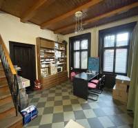 An interior with a wooden ceiling and a floor with decor, contains a table with chairs and shelves.