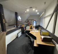 Office in a building with wooden beams, equipped with desks and office supplies.