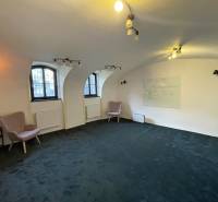 The interior of a building with arched windows, green carpet, and a wall board.
