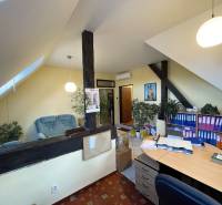 An office in a building with a wood-patterned floor, shelves for documents, and a seating area.