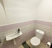 A restroom in a building with light pink tiles and a ceramic sink.