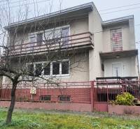A family house in Dlhá nad Váhom with a concrete facade, a balcony, and a front garden.
