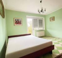 A bedroom in a family house with a bed, pastel walls, and a checkered floor.