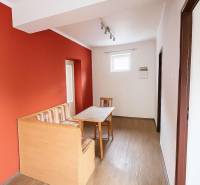 A dining room in a family house with a red wall and a wooden decor floor.