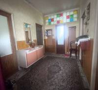 The hallway in the family house has a carpet and colorful stained glass windows above the doors.