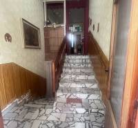 A staircase with mosaic tiles, wooden railing, and decorative wallpaper in a family house.