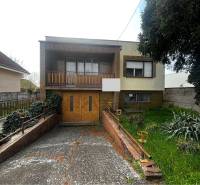 A family house in Šaľa with a garage, balcony, and garden, surrounded by vegetation and a fence.