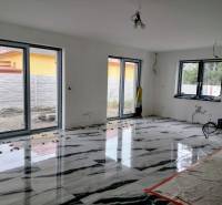 The living room of a family house with a glossy floor featuring a marble design and large windows.