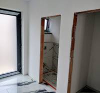 The interior of a family house with white walls and a marble-patterned floor.